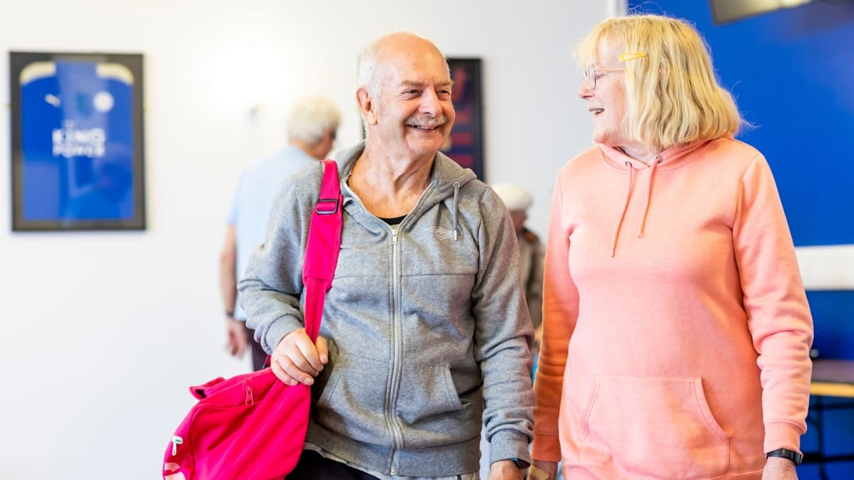 Two smiling older adults arriving at the gym together